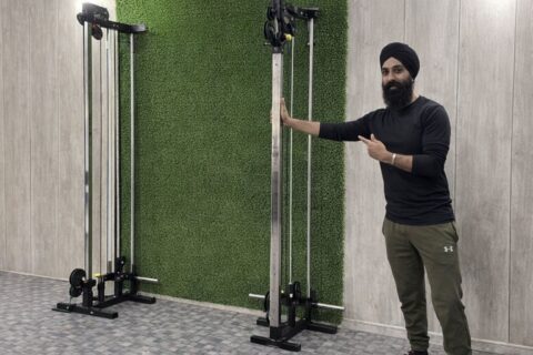 En man i turban pekar på en cable cross-maskin i ett gym.